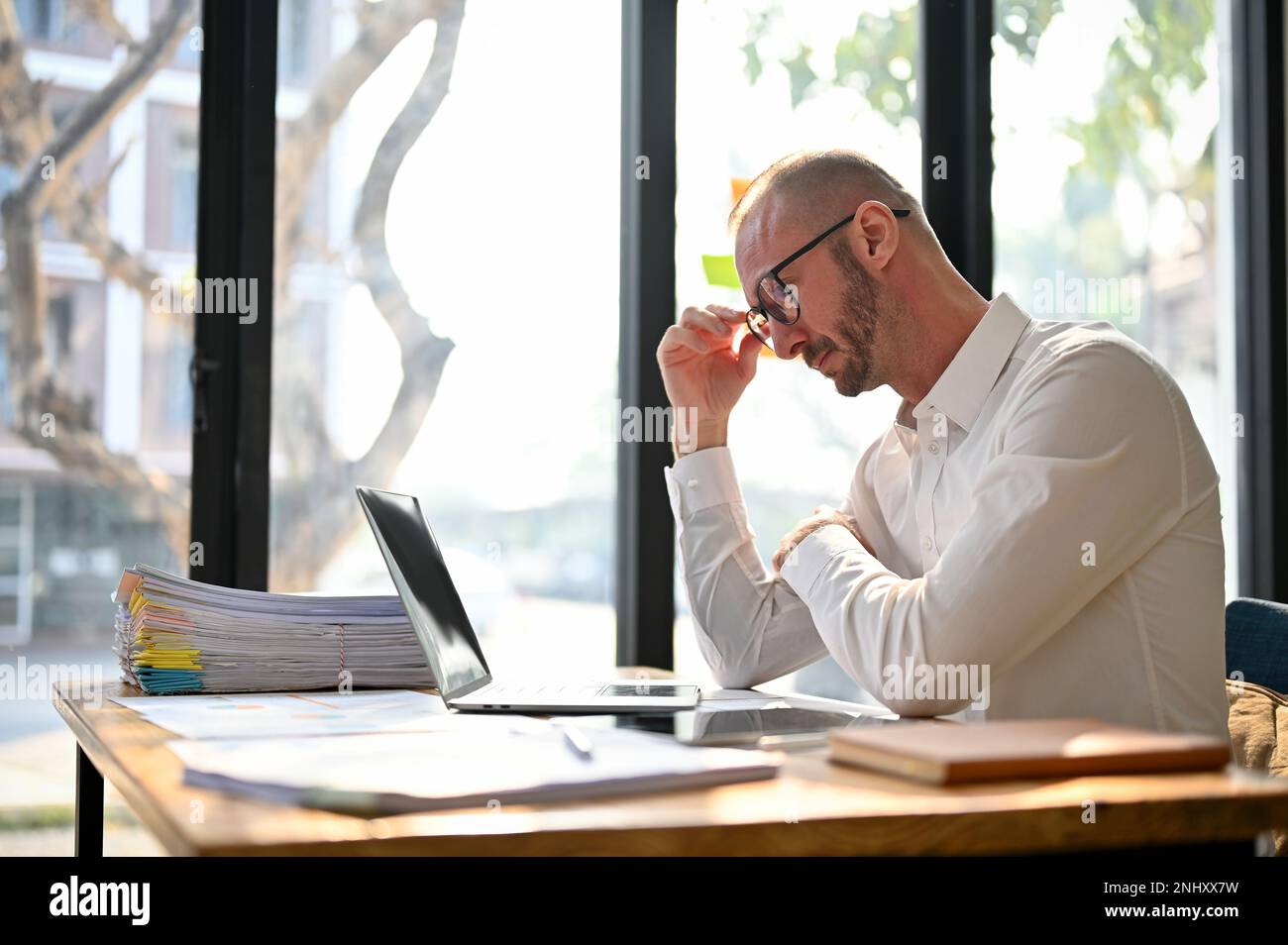 Professionista e focalizzato uomo d'affari caucasico o capo maschio penosamente pensando al suo progetto, prendendo decisioni serie, progettando il progetto, lavorando Foto Stock
