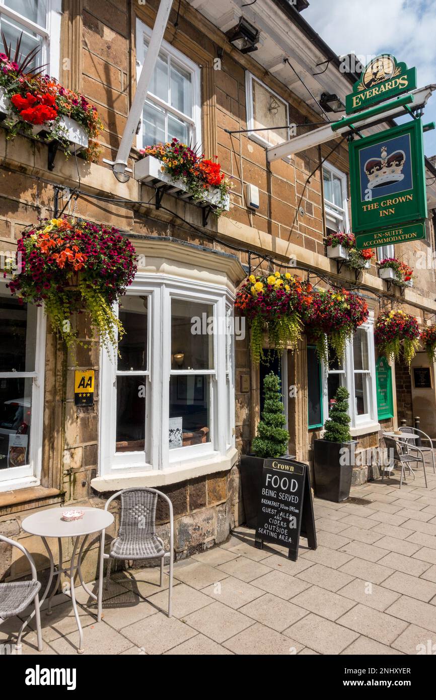 Bella mostra di fiori in cestini appesi e finestre di fronte al Crown Inn nel mese di luglio, Uppingham, Rutland, Inghilterra, Regno Unito Foto Stock