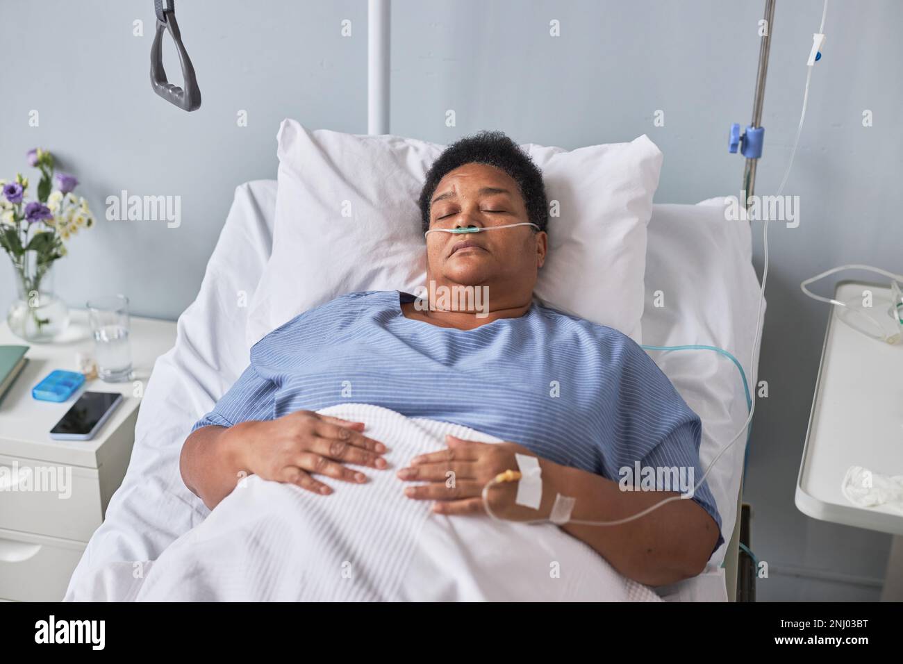 Donna anziana nera che posa sul letto nella stanza dell'ospedale con supporto IV, vista ad angolo alto Foto Stock