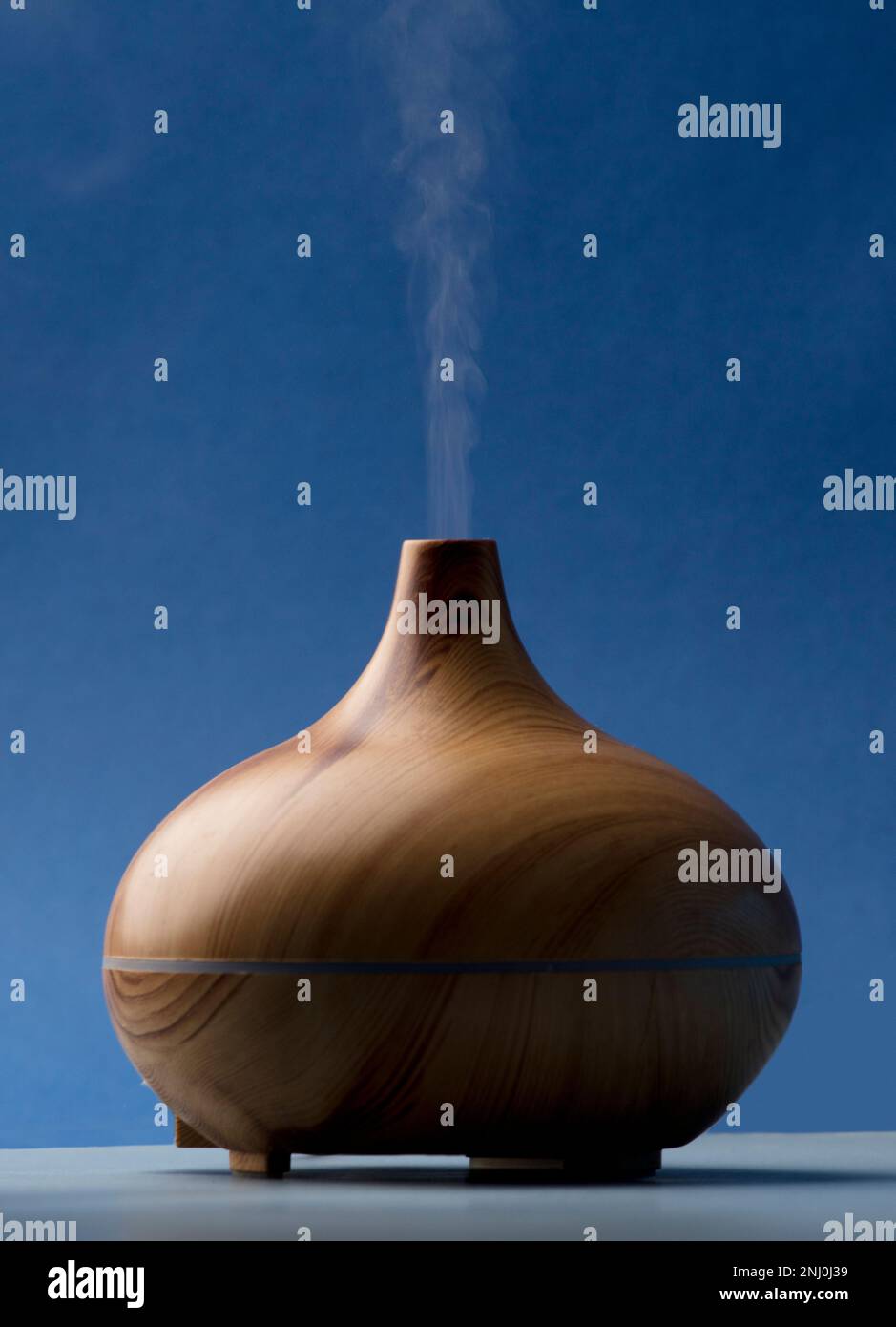 Vaporizzatore in legno con vapore di oli naturali, sul tavolo grigio del soggiorno Foto Stock