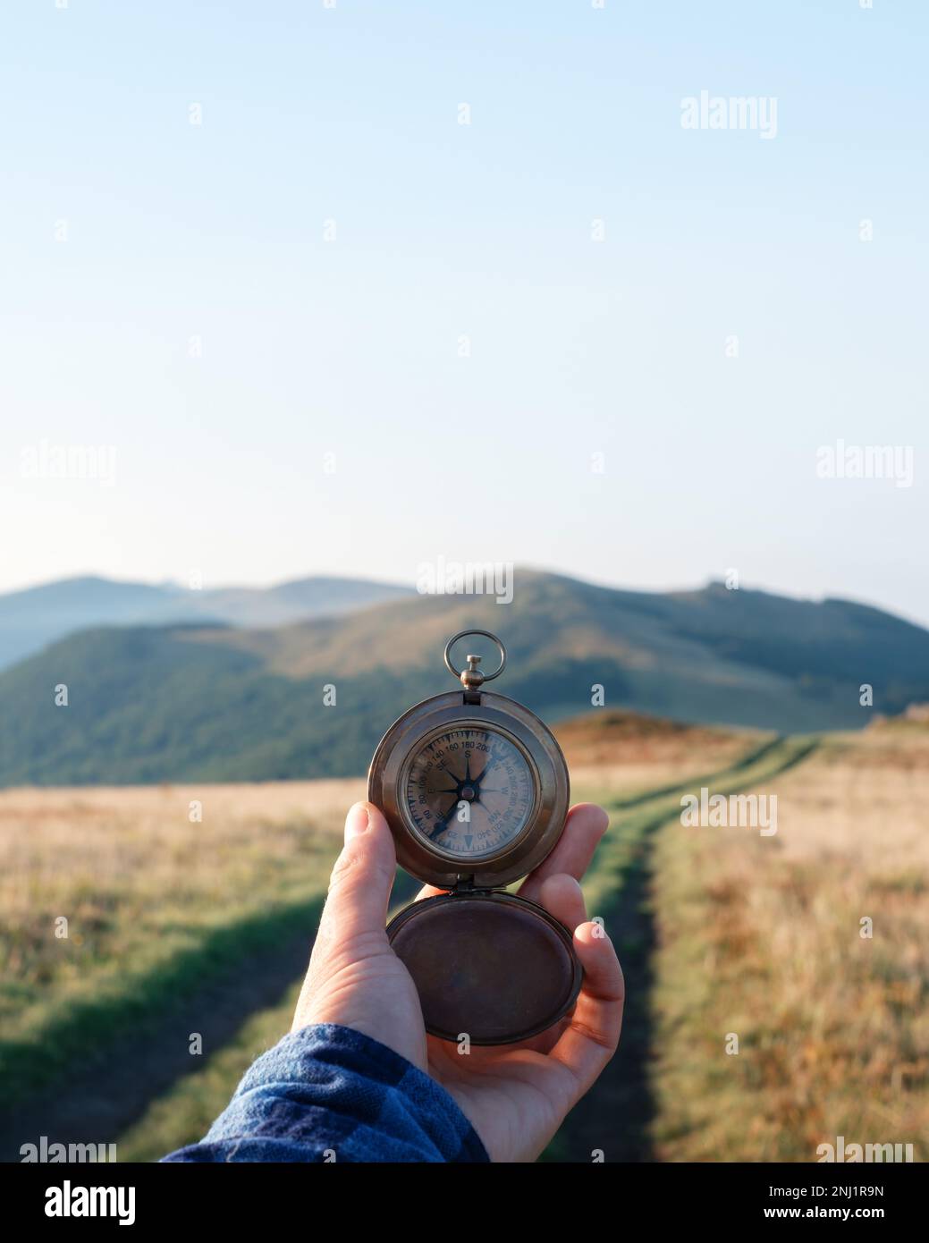 L'uomo con la bussola in mano sulla strada delle montagne. Concetto di viaggio. Fotografia di paesaggi Foto Stock