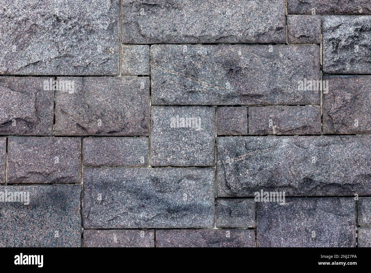 Vecchio muro grigio fatto di blocchi di granito ruvido. Primo piano della texture della foto di sfondo Foto Stock