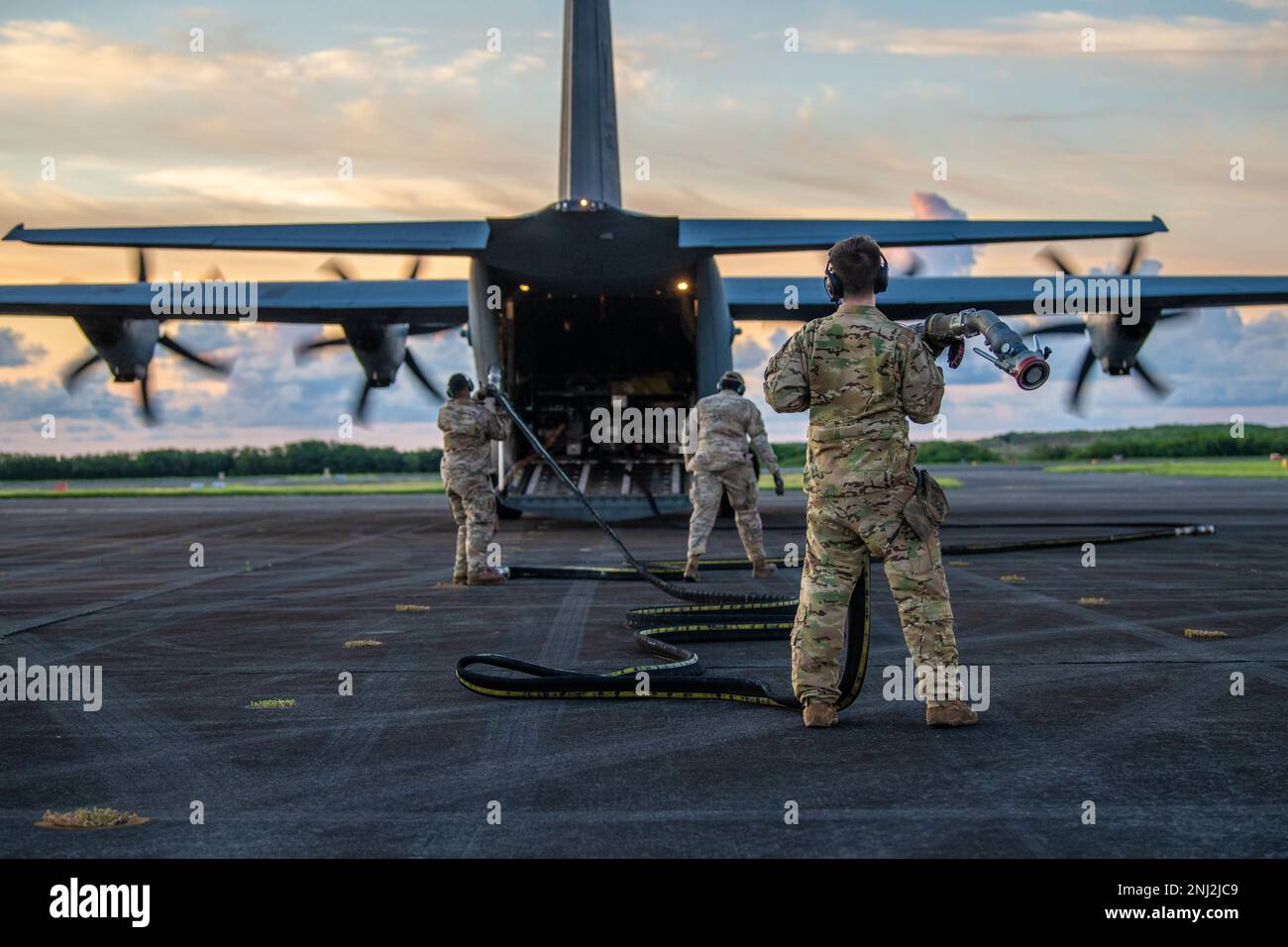 I militari dello Squadrone di preparazione di logistica 374th trasportano un tubo del combustibile verso un C-130J Super Hercules assegnato allo Squadrone di sollevamento di Airlift 36th all'aeroporto di Iwo Jima, Giappone, 4 agosto 2022. I modelli 36th AS e 374th LRS hanno fornito carburante per aiutare Marines a stabilire un punto di rifornimento aereo direttamente dopo l'atterraggio, mostrando come gli aerei possono diventare auto-serventi in ambienti austeri. Foto Stock