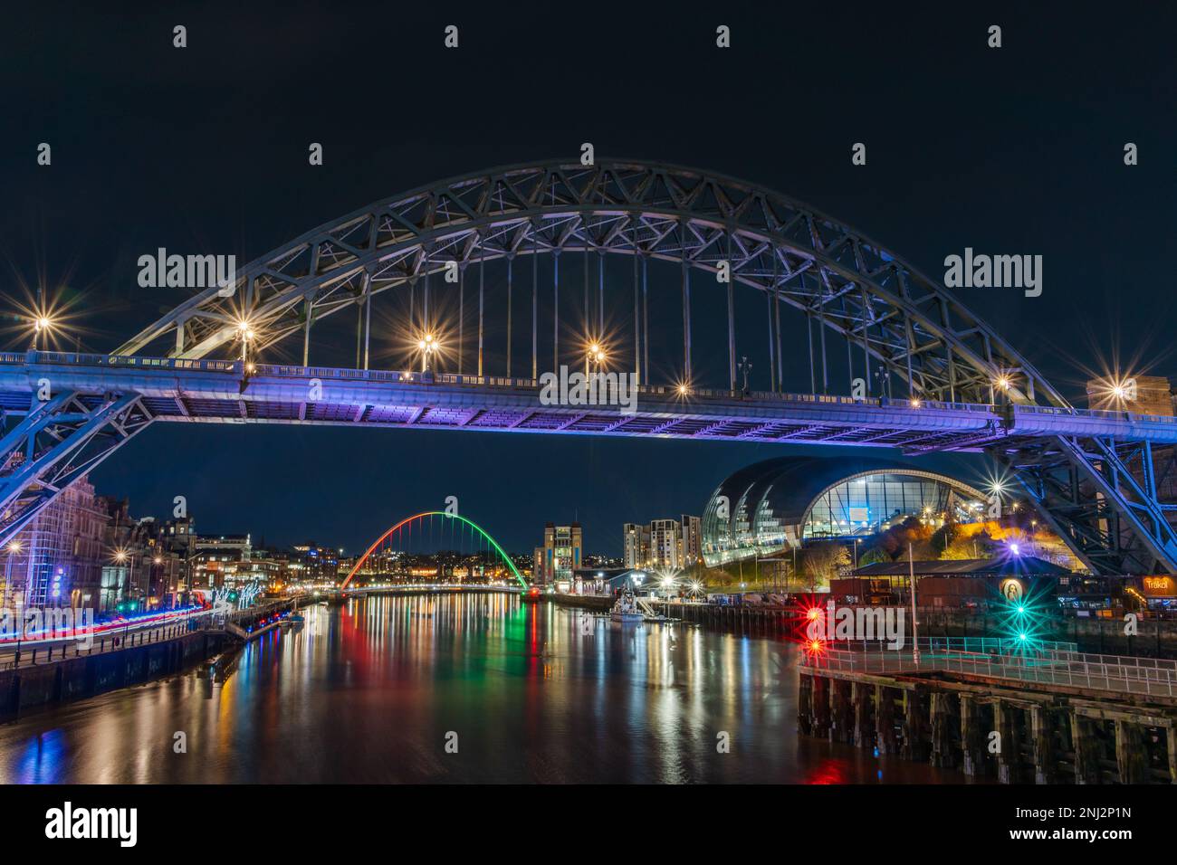 Newcastle upon Tyne, Regno Unito di notte. Mostra il Tyne Bridge, la Glasshouse, il Gateshead Millennium Bridge illuminato e i riflessi sul fiume. Foto Stock