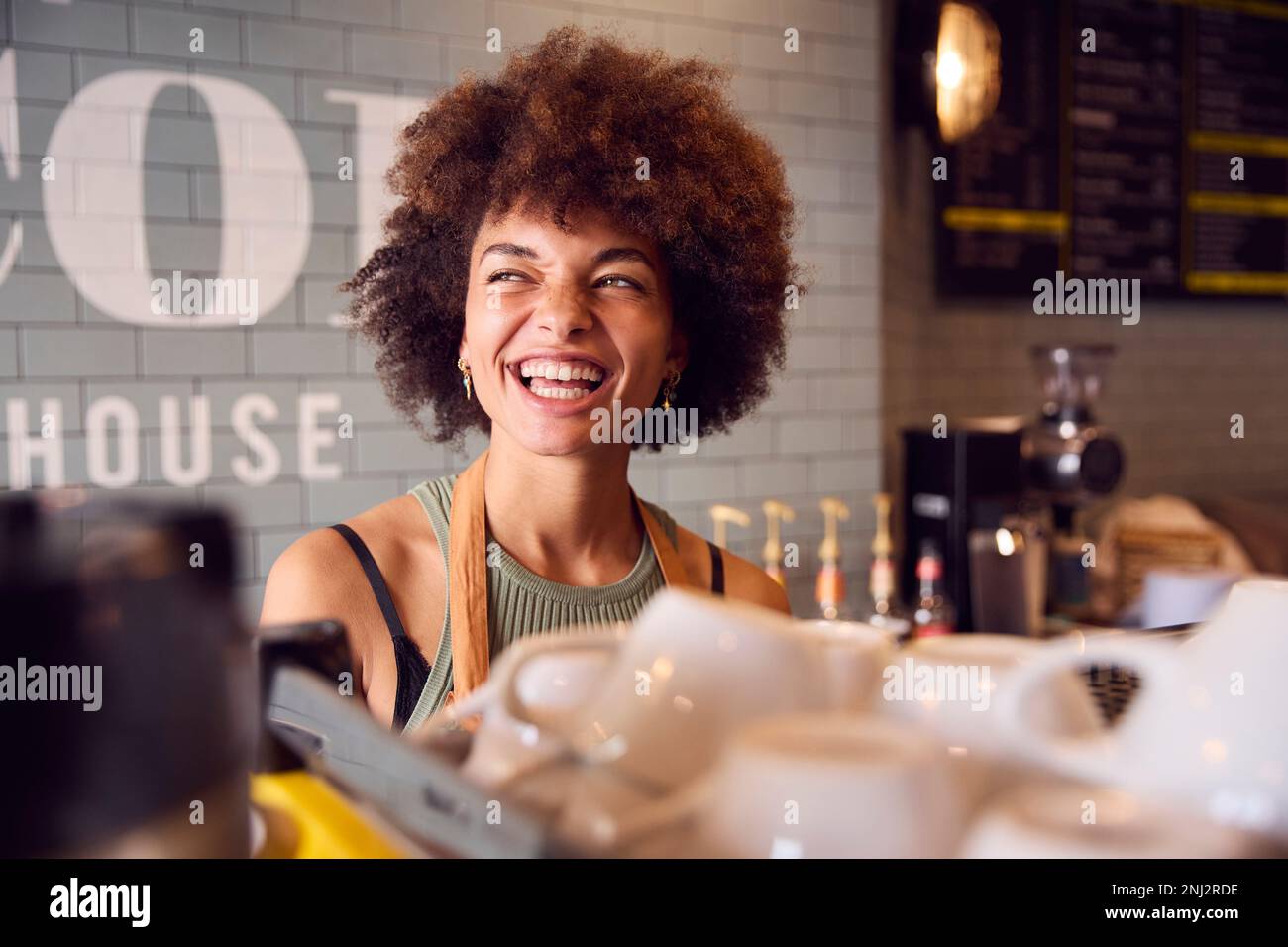 Sorridente proprietaria o personale femminile che serve dietro il bancone del Coffee Shop Foto Stock