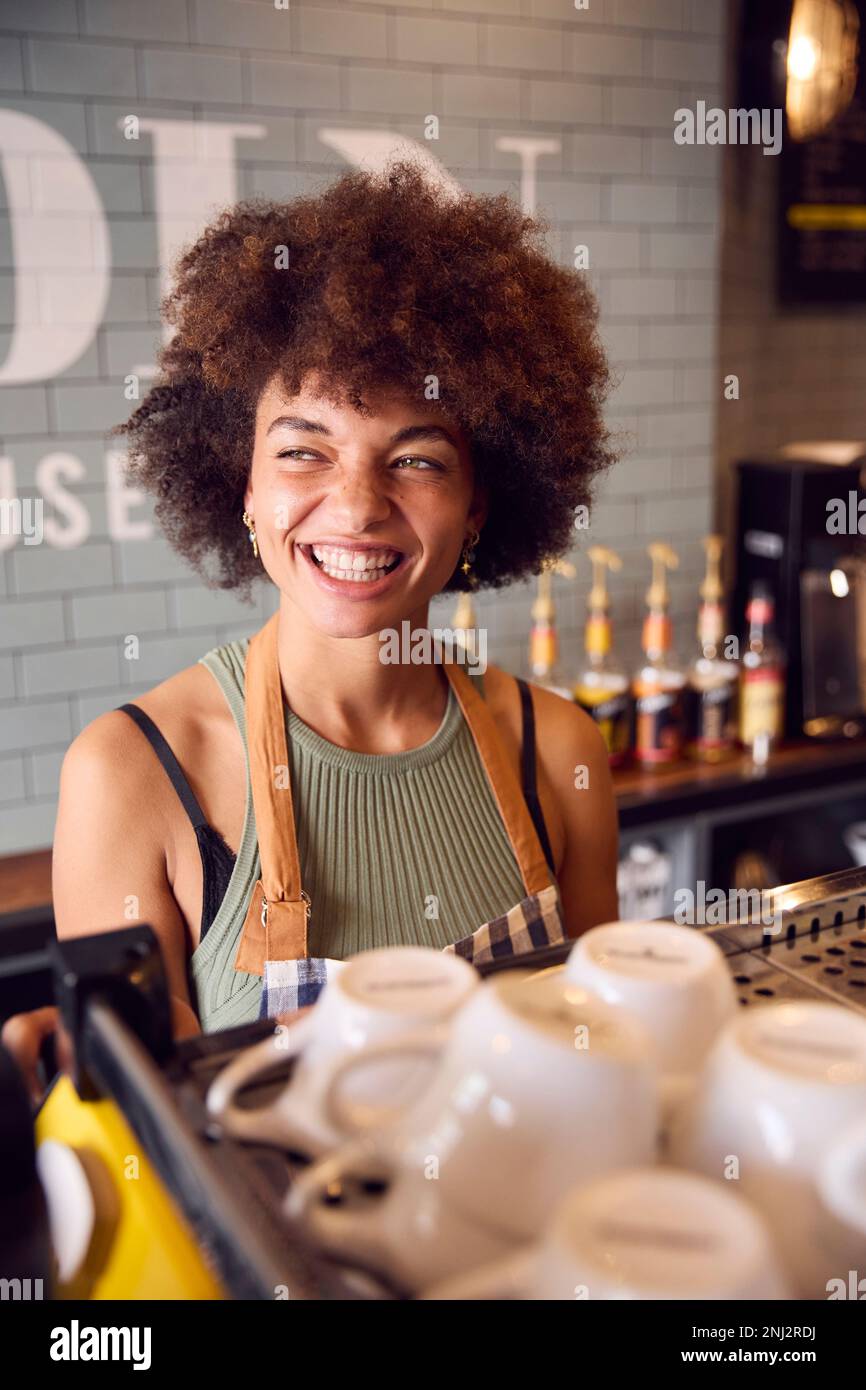 Sorridente proprietaria o personale femminile che serve dietro il bancone del Coffee Shop Foto Stock