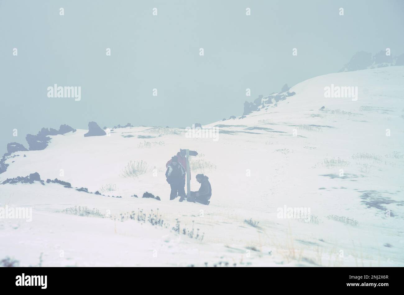 Piccolo gruppo di persone nella nebbia sulla 'Schiena dell'Asino' nel Parco Nazionale dell'Etna, ai margini della 'Valle del Bove', Sicilia, Italia Foto Stock