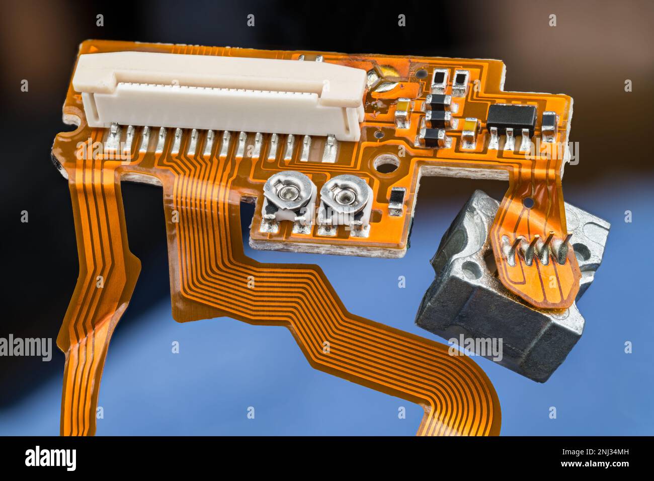 Scheda a circuito stampato arancione con cavi a nastro flessibili, piccoli componenti elettronici e connettore bianco. PCB all'interno dell'unità disco ottico CD/DVD digitale. Foto Stock