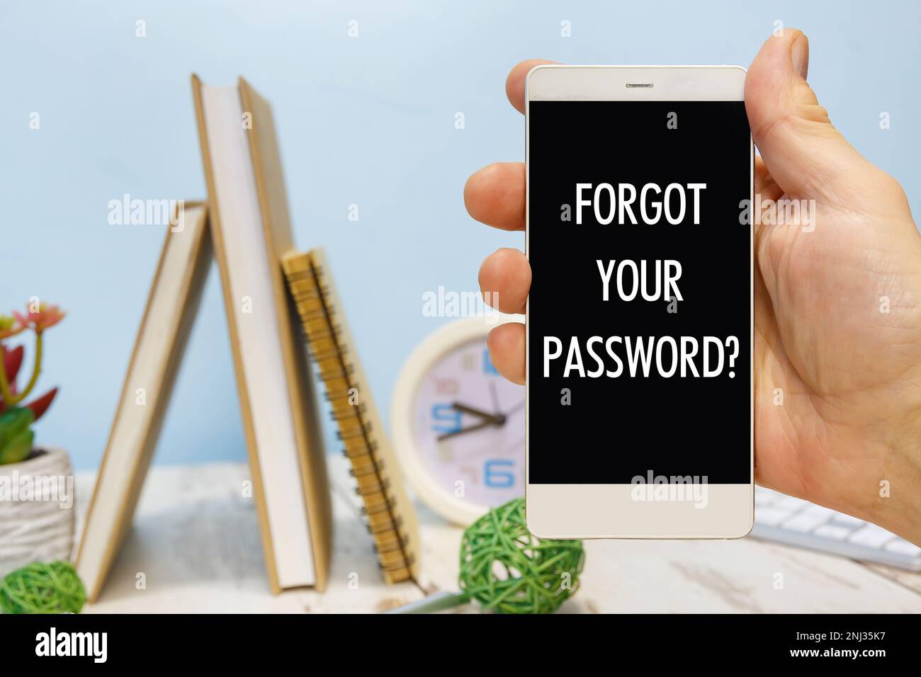 Smartphone in mano con l'iscrizione - Password dimenticata accanto ai materiali di consumo per ufficio Foto Stock