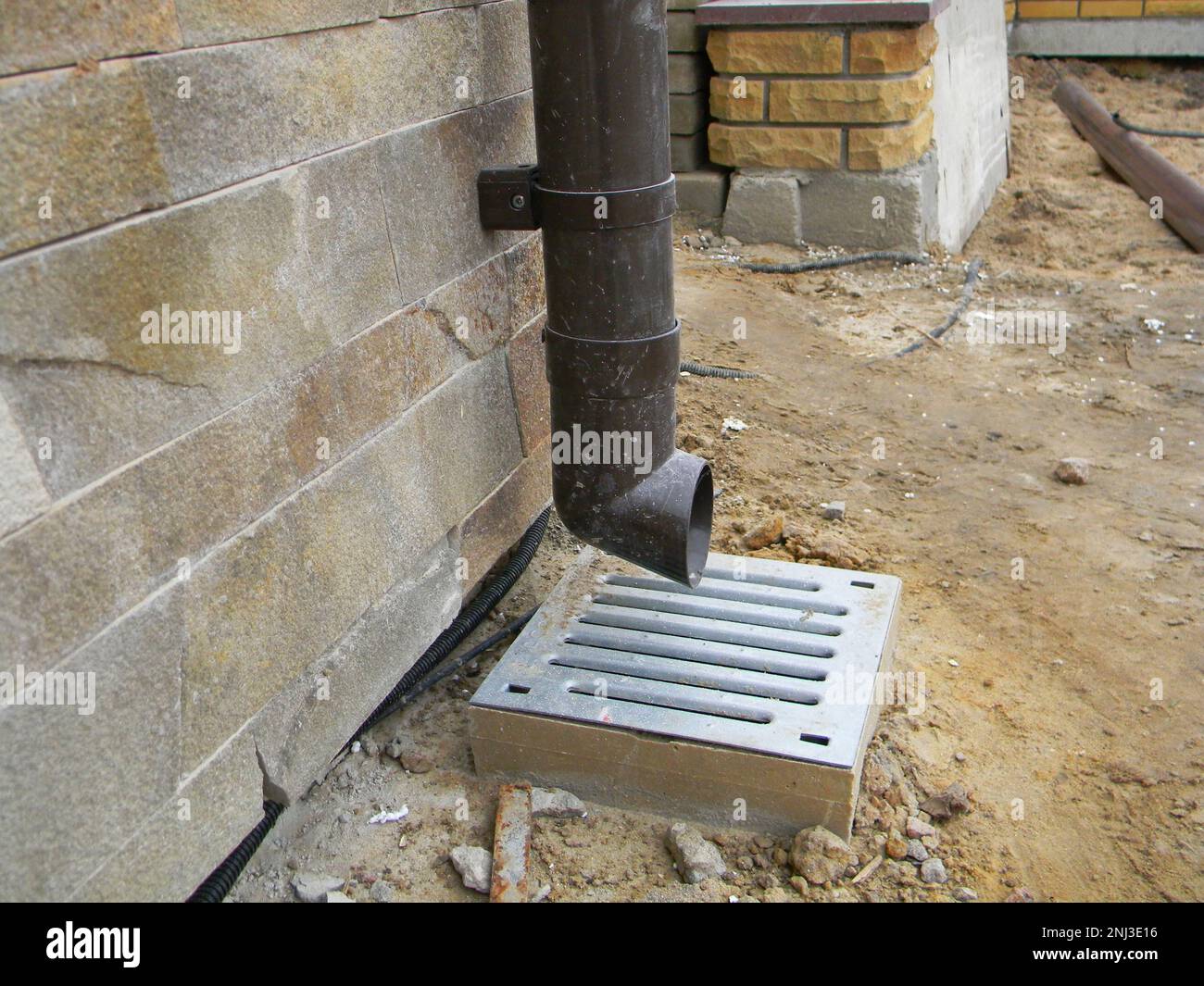 Primo piano sul tubo di scarico del gocciolatoio con foro di scarico sul cantiere edile. Costruzione di scarico di grondaia. Primo piano di drenaggio delle canaletta sotterranee. Foto Stock