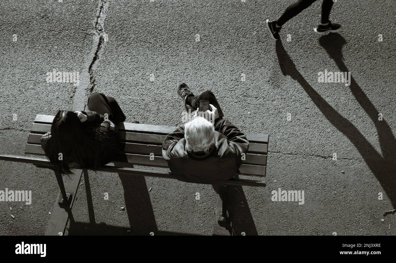 Vista guardando giù su due persone, uomo e donna seduto su Una panchina con Un Jogger che corre passato sulle rive del fiume Senna, Parigi Francia Foto Stock