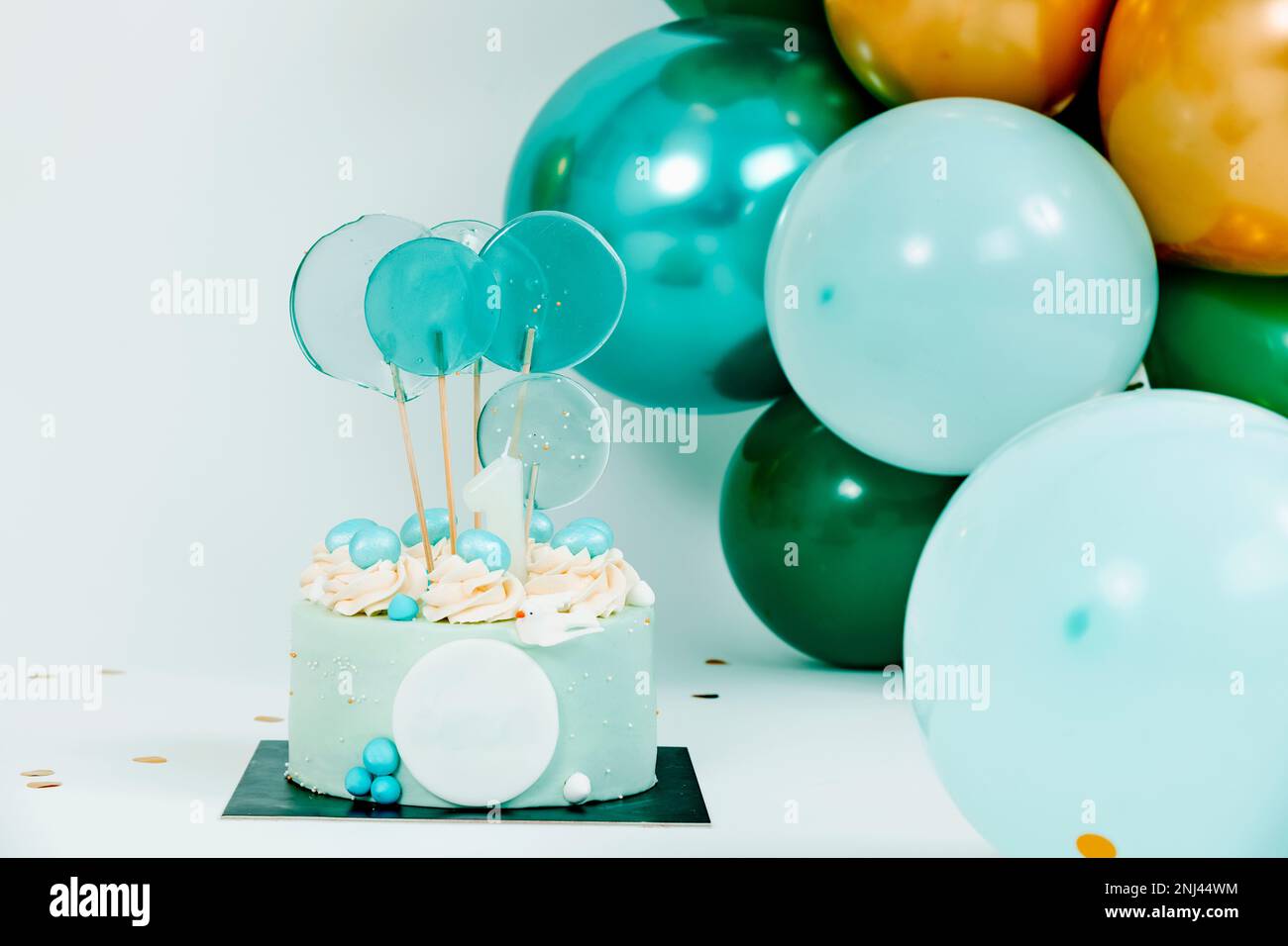 una torta blu ed alcuni palloncini di colori e dimensioni differenti che formano una disposizione elegante come decorazione per una festa di compleanno un matrimonio o un bambino ca Foto Stock
