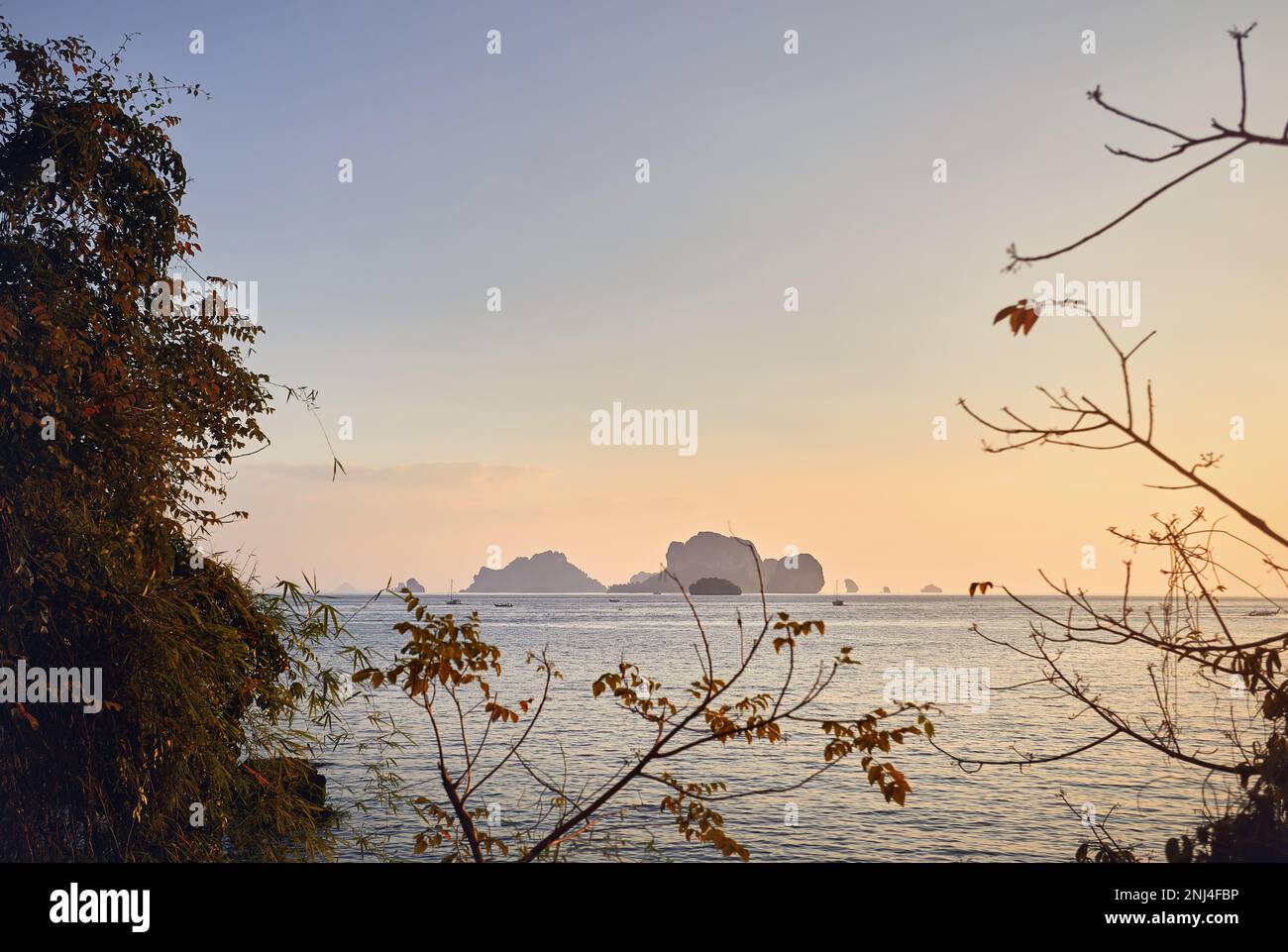 Bella isola tropicale a baia incorniciata da alberi al tramonto nel Mare delle Andamane, Thailandia Foto Stock