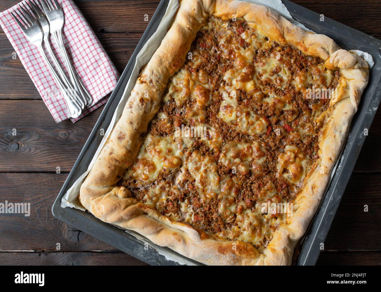 Pizza di manzo macinata con formaggio su una teglia isolata su fondo di legno scuro Foto Stock