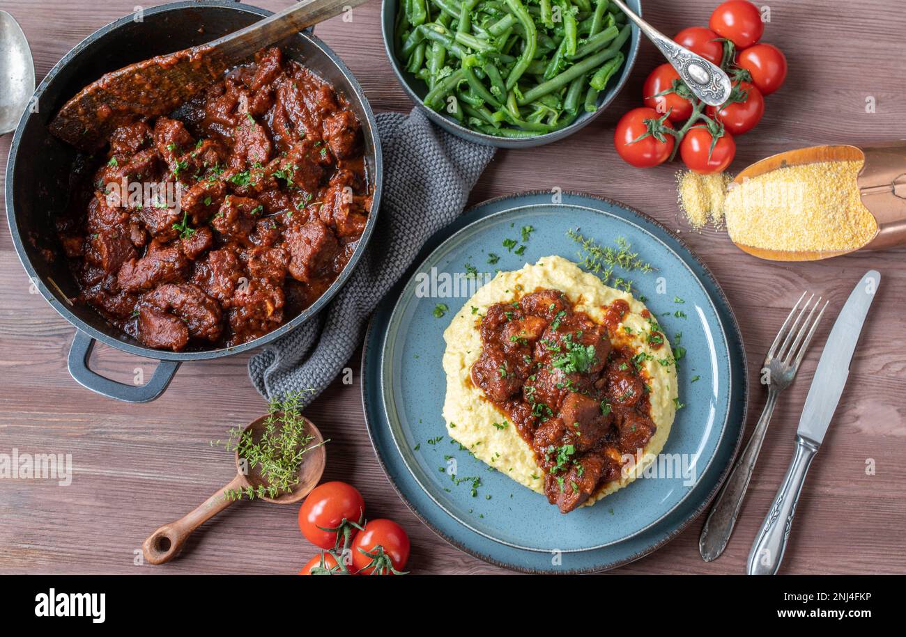 Stufato di maiale con polenta cremosa e fagiolini. Delizioso piatto di carne senza glutine la domenica o la festa Foto Stock