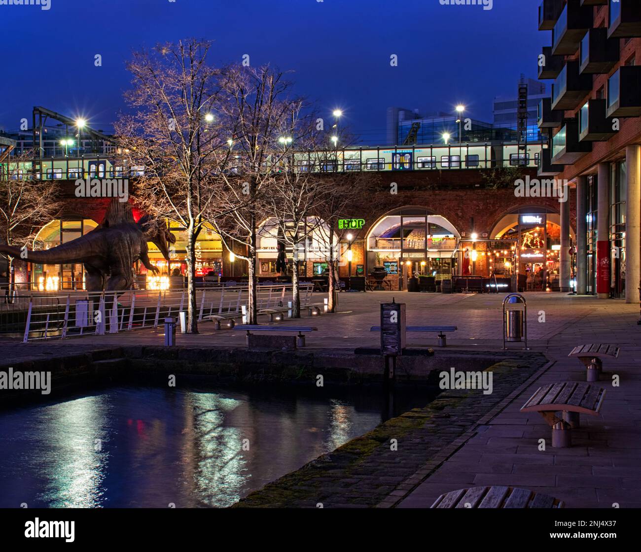 Il centro illuminato di notte di Granary Wharf, con un dinosauro modello a sinistra dell'immagine Foto Stock