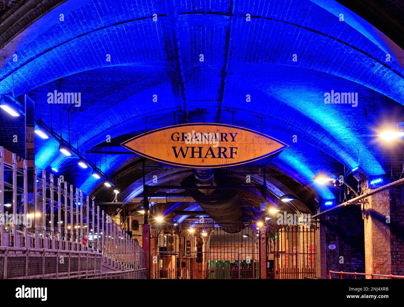 Un tunnel con un cartello sospeso Granary Wharf sotto la stazione centrale di Leeds. Illuminato da luce artificiale Foto Stock
