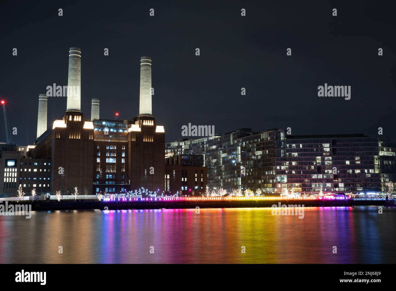 I camini della centrale elettrica di Battersea, recentemente ristrutturata, sono illuminati e sul lungofiume è presente uno spettacolo di luci con un'opera d'arte luminosa per persone che saltellano. Foto Stock