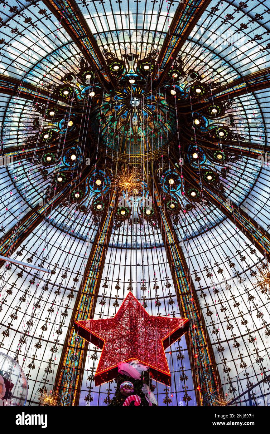 La cupola dell'edificio a Galeries Lafayette, il grande magazzino parigino. Nella cornice è la stella sulla cima dell'albero di Natale. Foto Stock