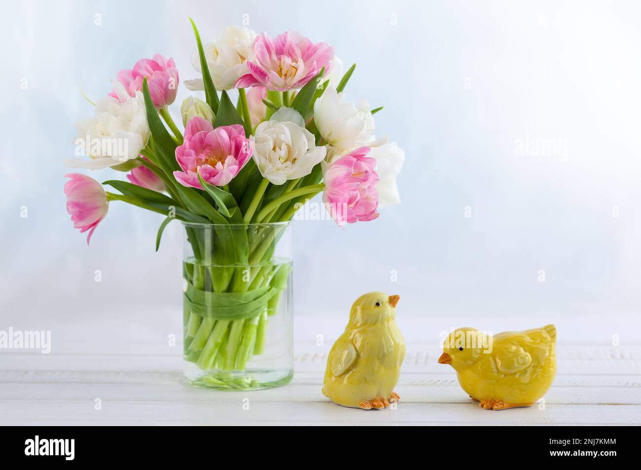 Bouquet pasquale di tulipani primaverili e decorazioni pasquali su tavolo di legno bianco. Concetto di Pasqua con spazio di copia. Foto Stock
