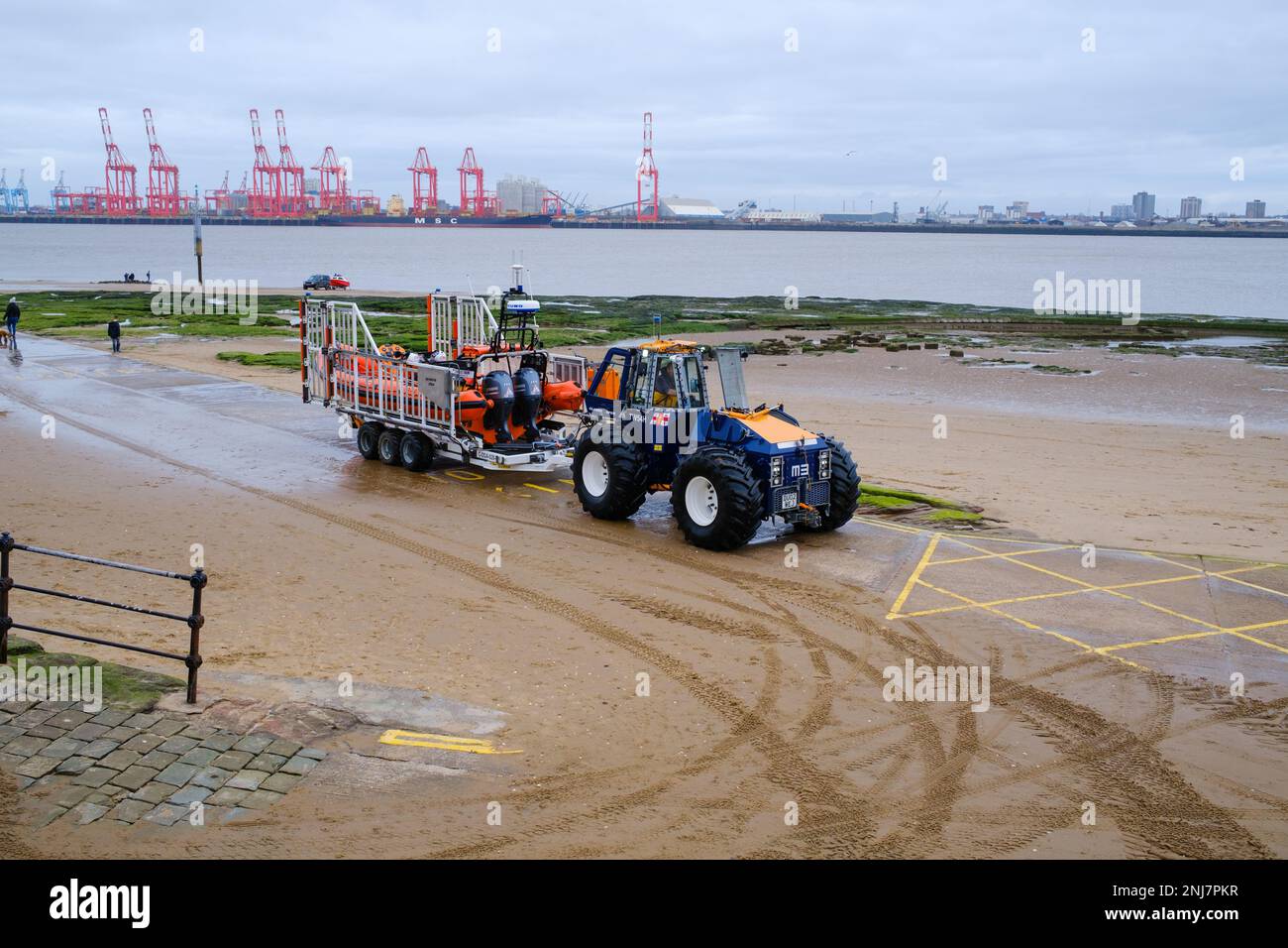Nuovo equipaggio di Brighton Life Boat recuperare la barca di nuovo sulla spiaggia con trattore trainare la costola su un rimorchio dopo aver completato un salvataggio in mare Foto Stock