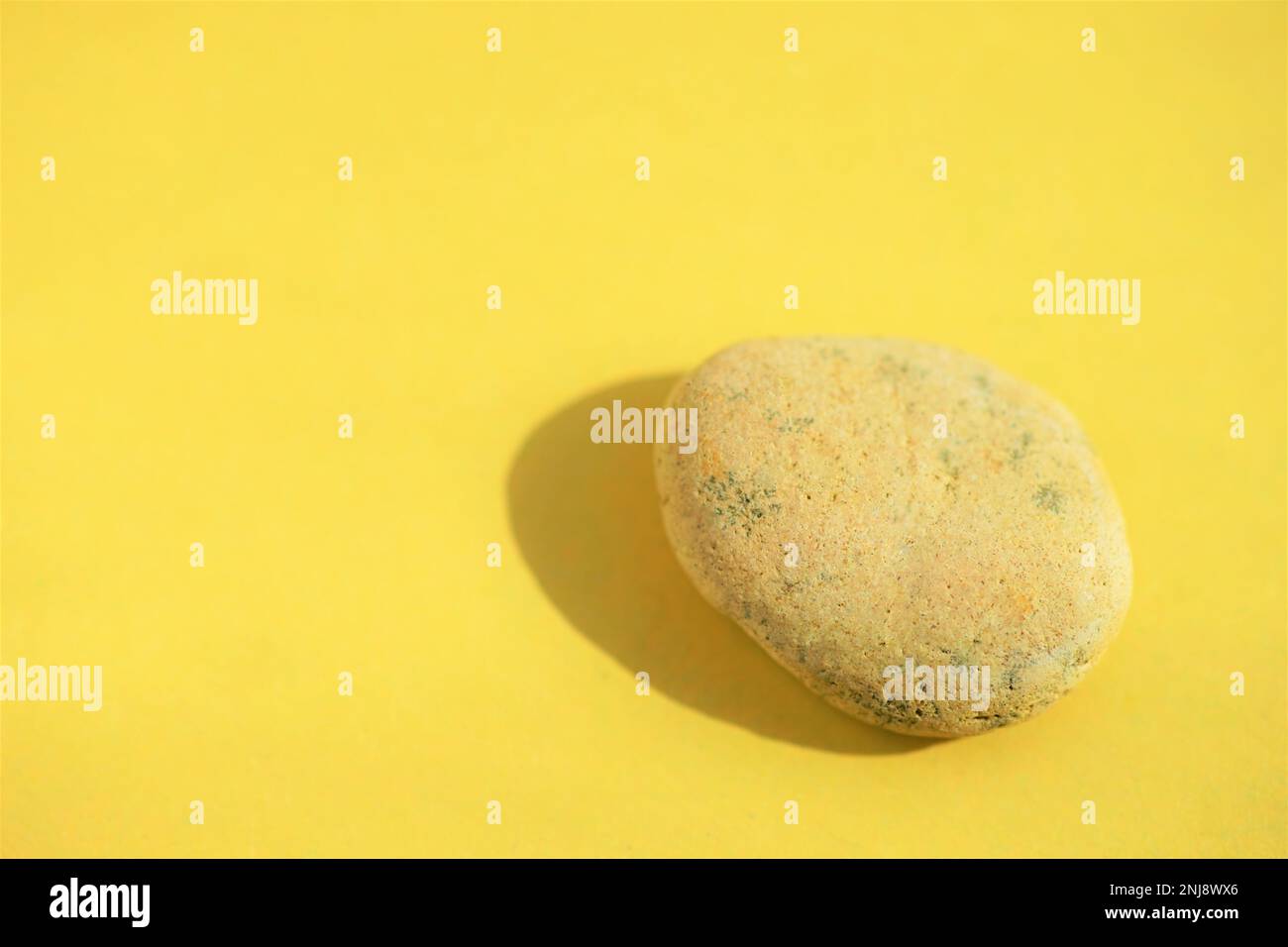 Pietra di ciottoli beige al tavolo giallo soleggiato. Foto Stock