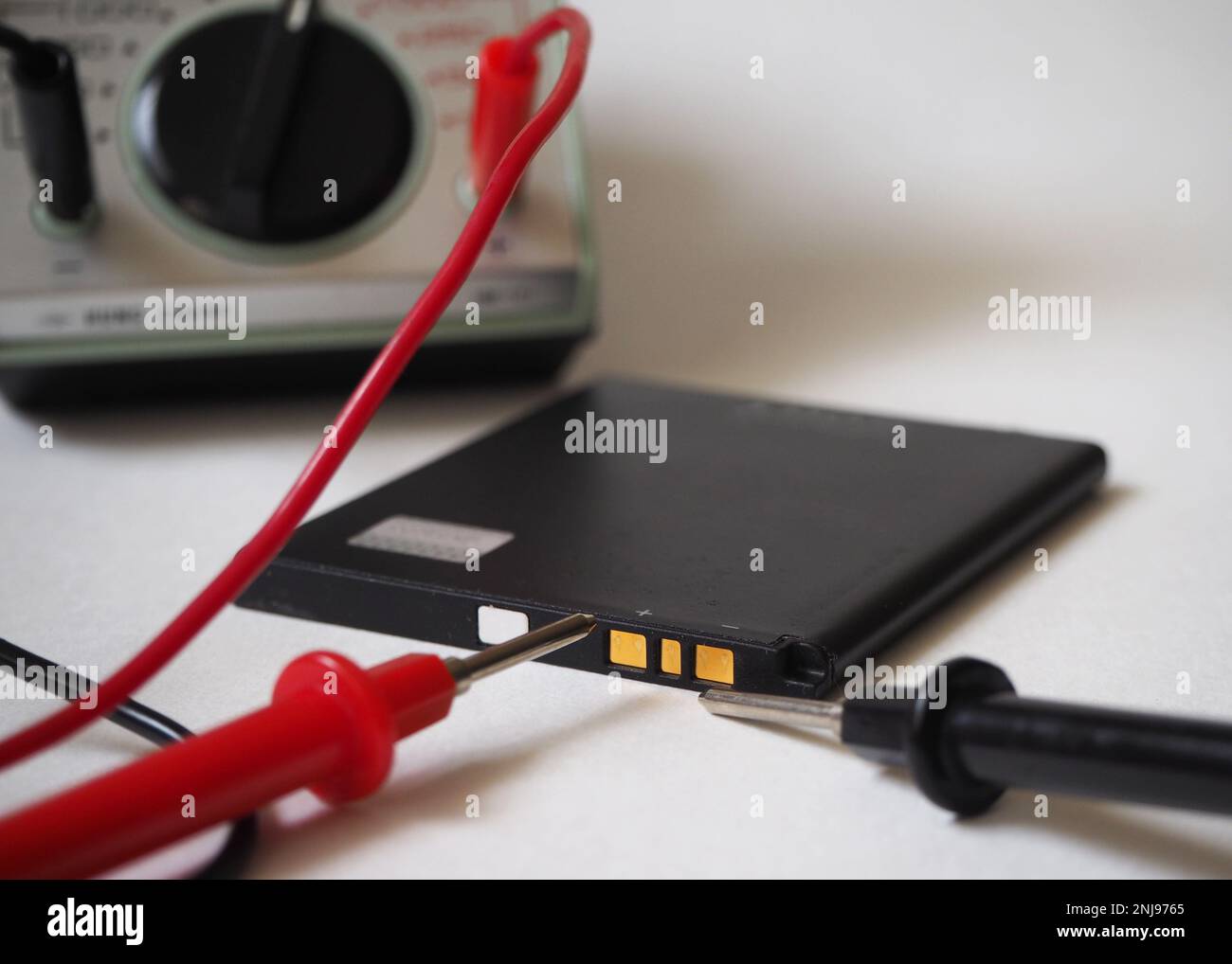 Test delle condizioni della batteria con voltmetro su sfondo bianco. Foto Stock