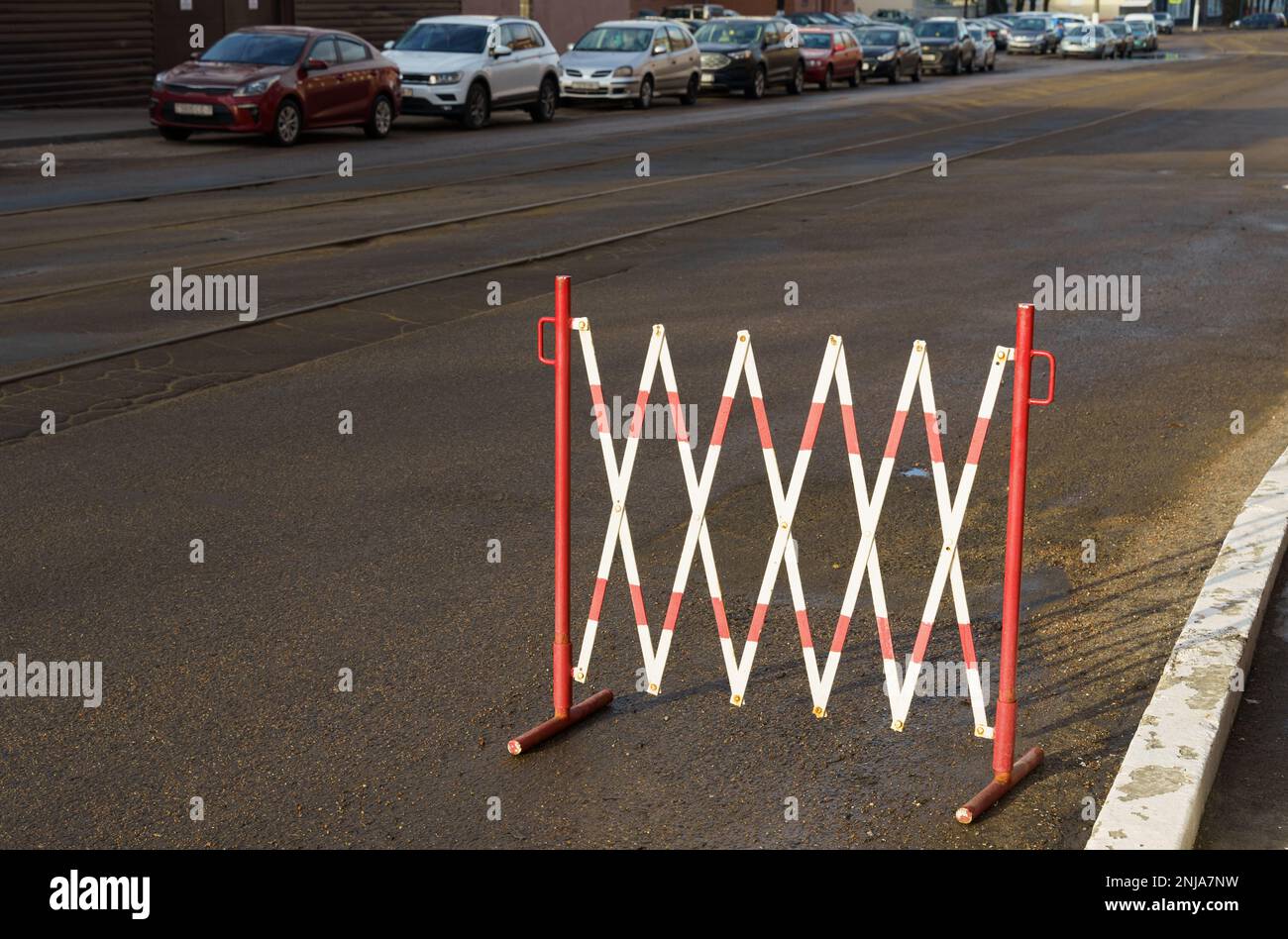 Recinzione temporanea restrittiva di colore rosso e bianco in un'area di parcheggio su una strada cittadina. Foto Stock