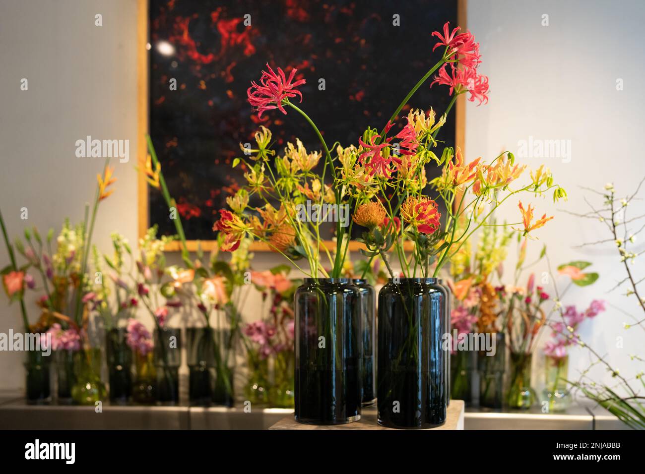 Vasi decorativi in vetro con fiori. Lillis di fiamma (Gloriosa superba) in primo piano. Foto Stock