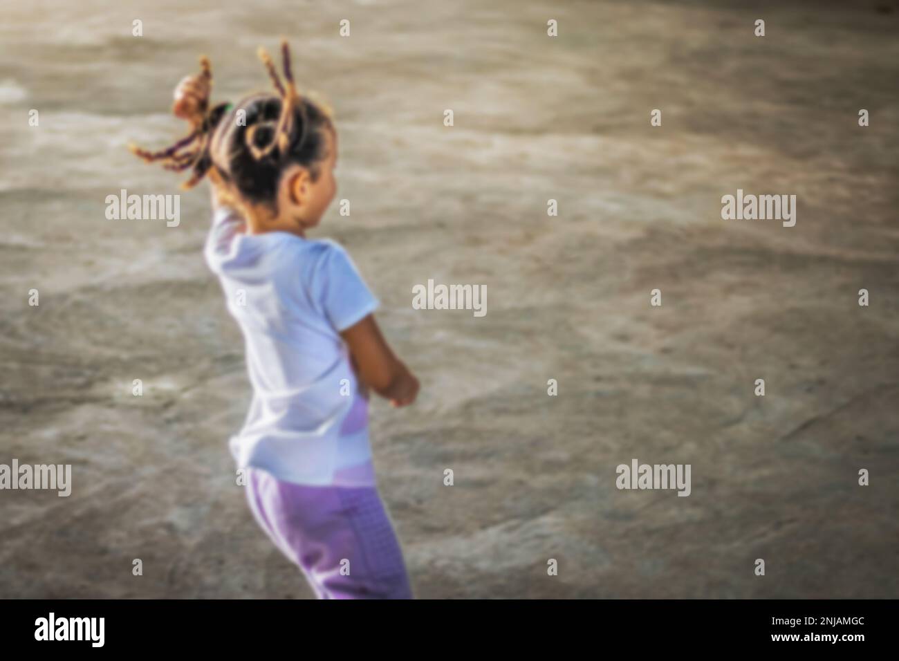 Foto sfocata di piccola ragazza brasiliana dalla parte posteriore che corre e gioca con trecce al vento, fanciulla defocusa, foto con area riservata per la scrittura Foto Stock