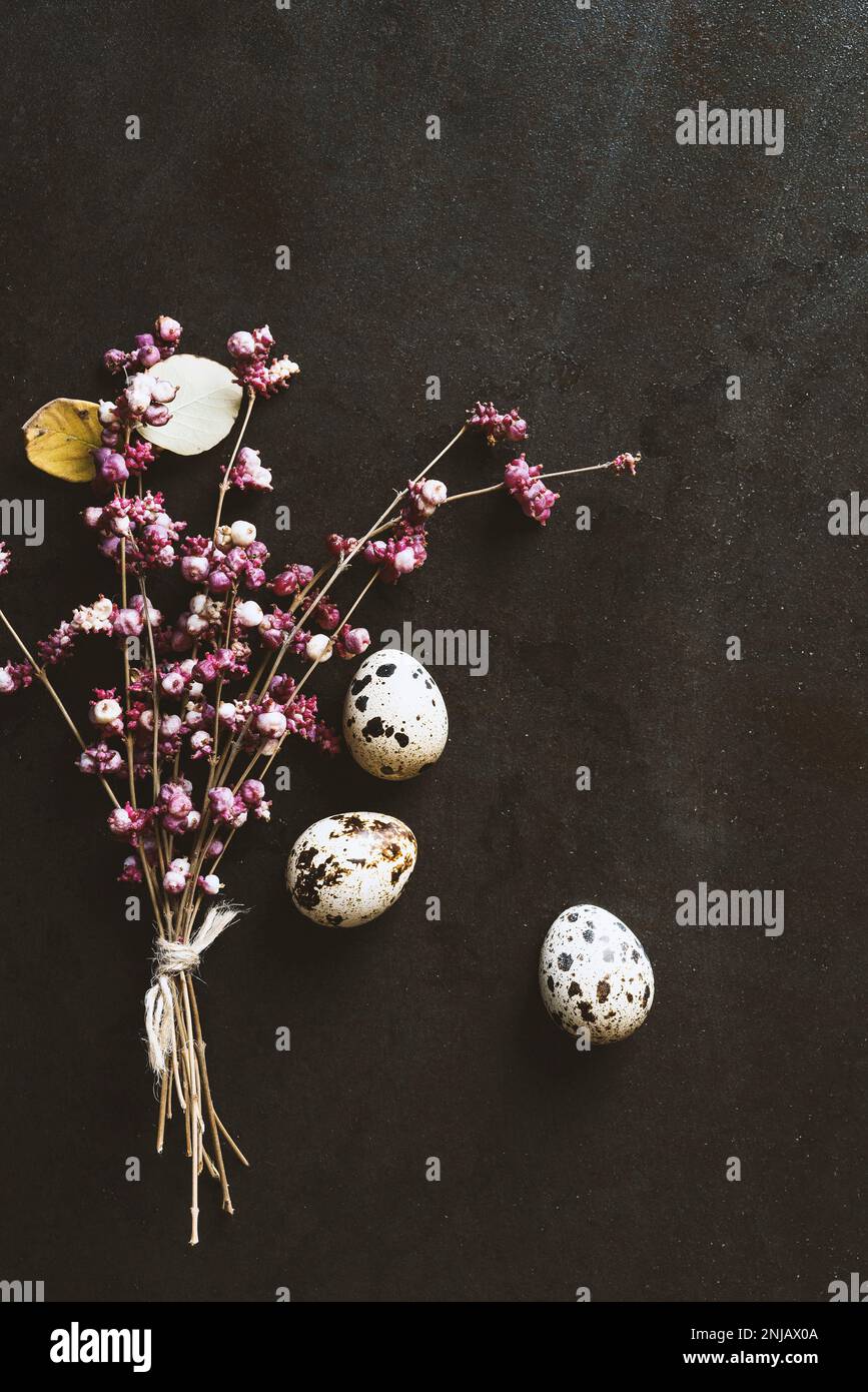 Uova di quaglia e un bouquet di fiori primaverili su sfondo rustico testurizzato Foto Stock