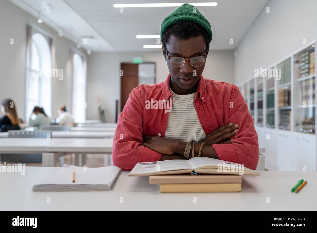 Studio concentrato studente di razza mista maschio si prepara per un importante test di borsa di studio della biblioteca universitaria Foto Stock