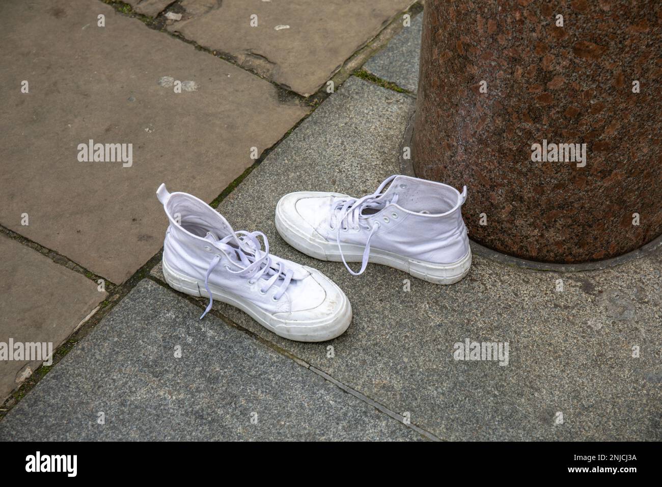 Sneaker da basket bianche abbandonate sul marciapiede o sul marciapiede Foto Stock