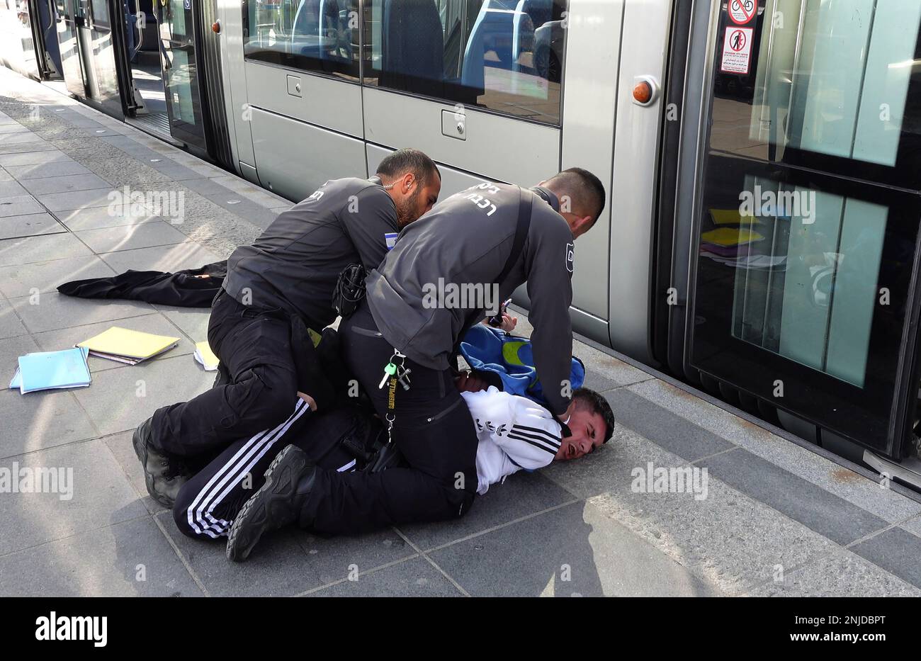 GERUSALEMME, ISRAELE - 22 FEBBRAIO: Le guardie di sicurezza Light Rail puntano un giovane palestinese a terra dopo averlo rimosso dalla macchina del treno, in una stazione del tram nel quartiere di Gerusalemme est di Beit Hanina il 22 febbraio 2023, a Gerusalemme, Israele. Alla luce dell'attuale ondata di attentati terroristici a Gerusalemme, il governo israeliano ha deciso di rafforzare le forze di sicurezza e di migliorare la sicurezza personale nella città. Tre compagnie di polizia di frontiera sono state mobilitate a Gerusalemme est a causa della crescente violenza nei quartieri palestinesi. Credit: Eddie Gerald/Alamy Live News Foto Stock