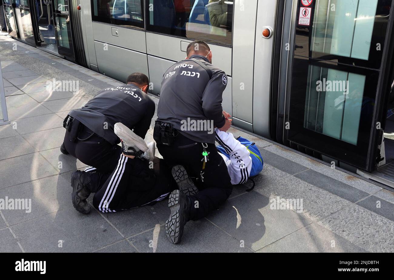 GERUSALEMME, ISRAELE - 22 FEBBRAIO: Le guardie di sicurezza Light Rail puntano un giovane palestinese a terra dopo averlo rimosso dalla macchina del treno, in una stazione del tram nel quartiere di Gerusalemme est di Beit Hanina il 22 febbraio 2023, a Gerusalemme, Israele. Alla luce dell'attuale ondata di attentati terroristici a Gerusalemme, il governo israeliano ha deciso di rafforzare le forze di sicurezza e di migliorare la sicurezza personale nella città. Tre compagnie di polizia di frontiera sono state mobilitate a Gerusalemme est a causa della crescente violenza nei quartieri palestinesi. Credit: Eddie Gerald/Alamy Live News Foto Stock