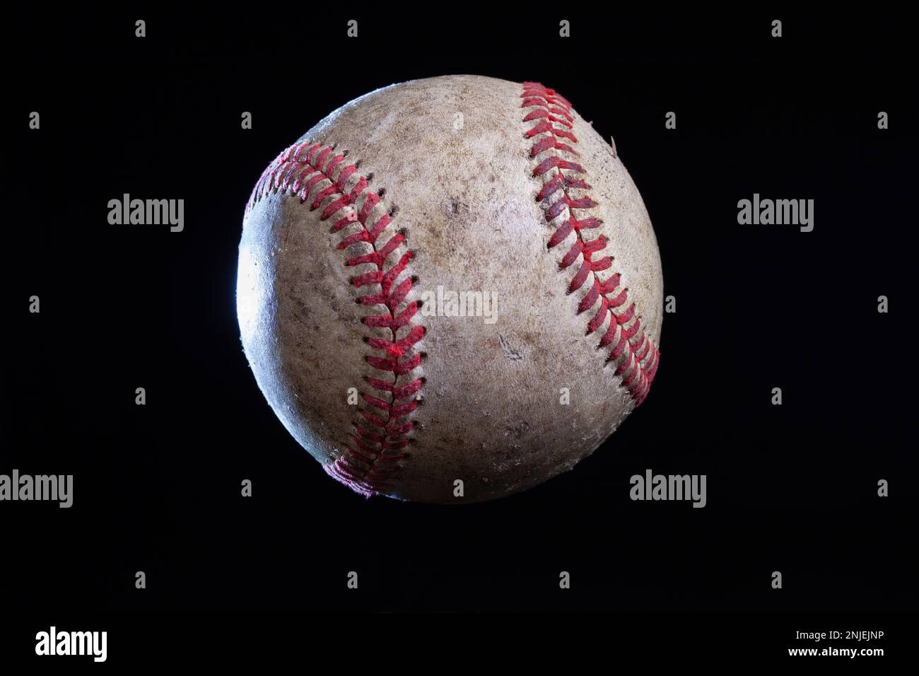Vecchio baseball ruvido con illuminazione drammatica isolato su uno sfondo nero Foto Stock