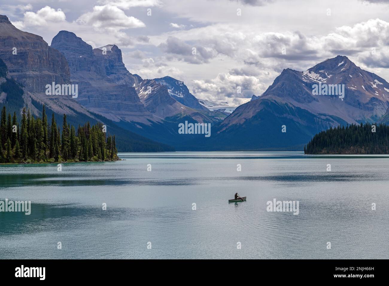 Uomo in canoa sul lago Maligne nelle montagne rocciose canadesi, il parco nazionale di Jasper, Alberta, Canada. Foto Stock