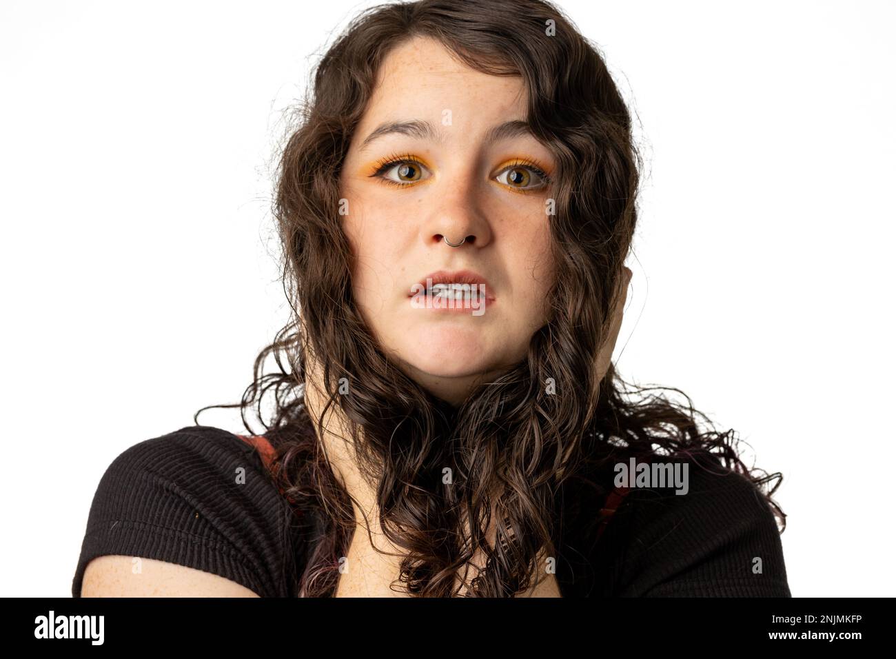 Giovane donna che si aggraffa il viso con frustrazione e stress, su sfondo bianco Foto Stock