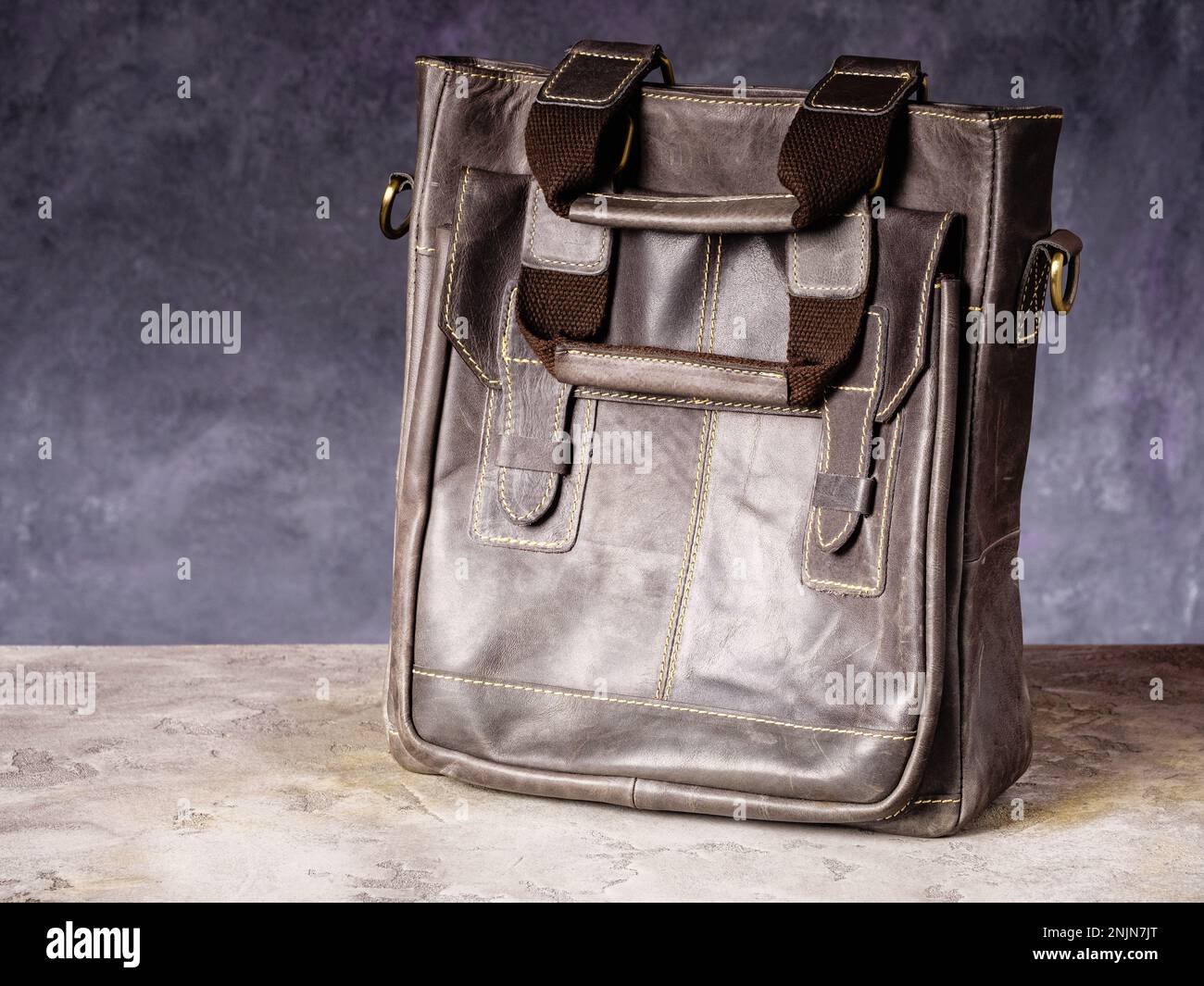 Borsa per uso quotidiano in pelle marrone con manici su sfondo grigio in cemento Foto Stock