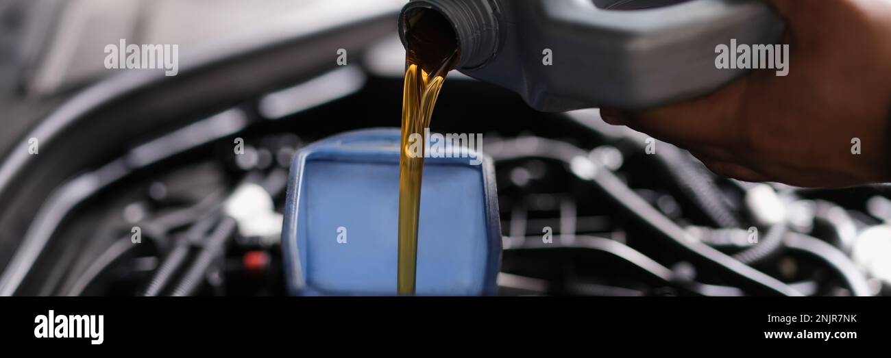 Versare l'olio per ingranaggi nell'auto attraverso l'annaffiatoio Foto Stock