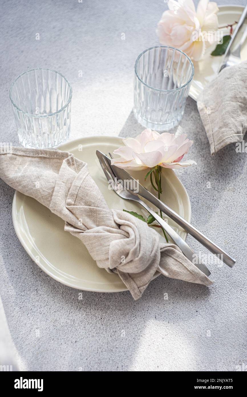 Tavolo con piastre in ceramica bianca e rose in fiore bianche Foto Stock