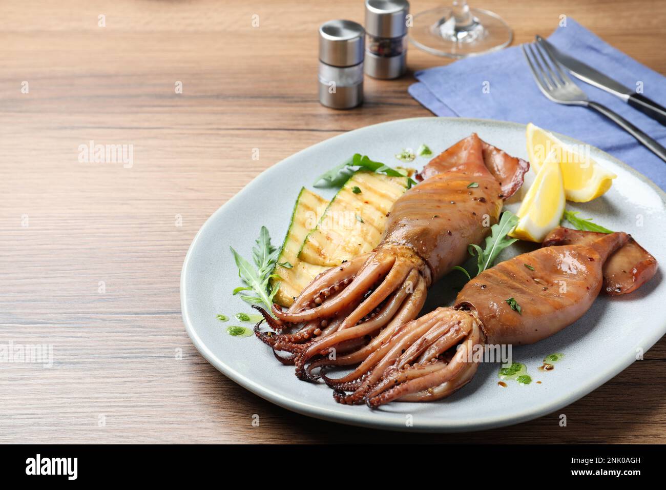 Deliziosi calamari alla griglia serviti su un tavolo di legno, spazio per il testo Foto Stock