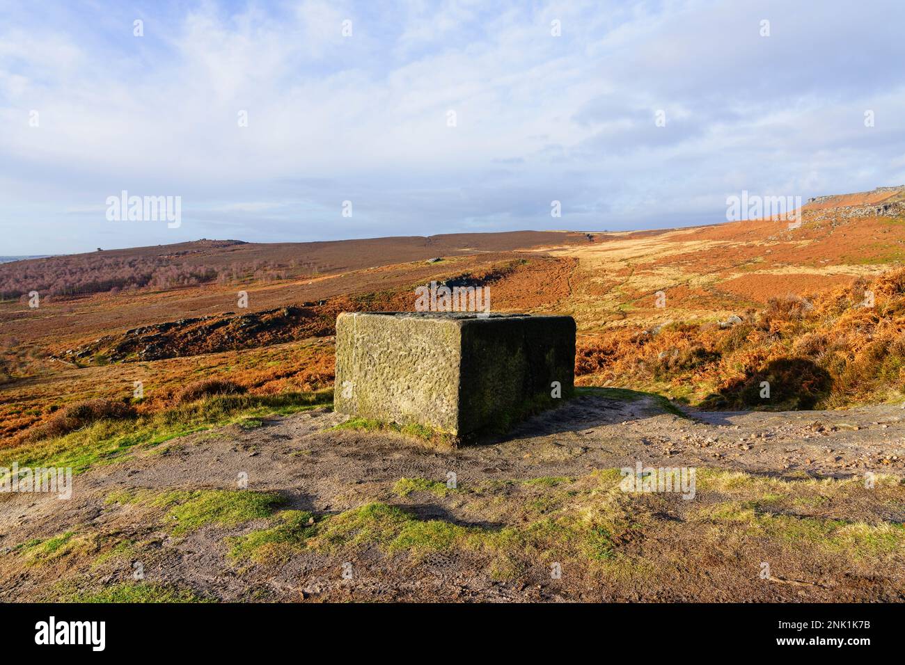 Trogolo di pietra non finito, rotto in piedi in alto sul bordo di Burbage nella luce del sole di inverno. Foto Stock