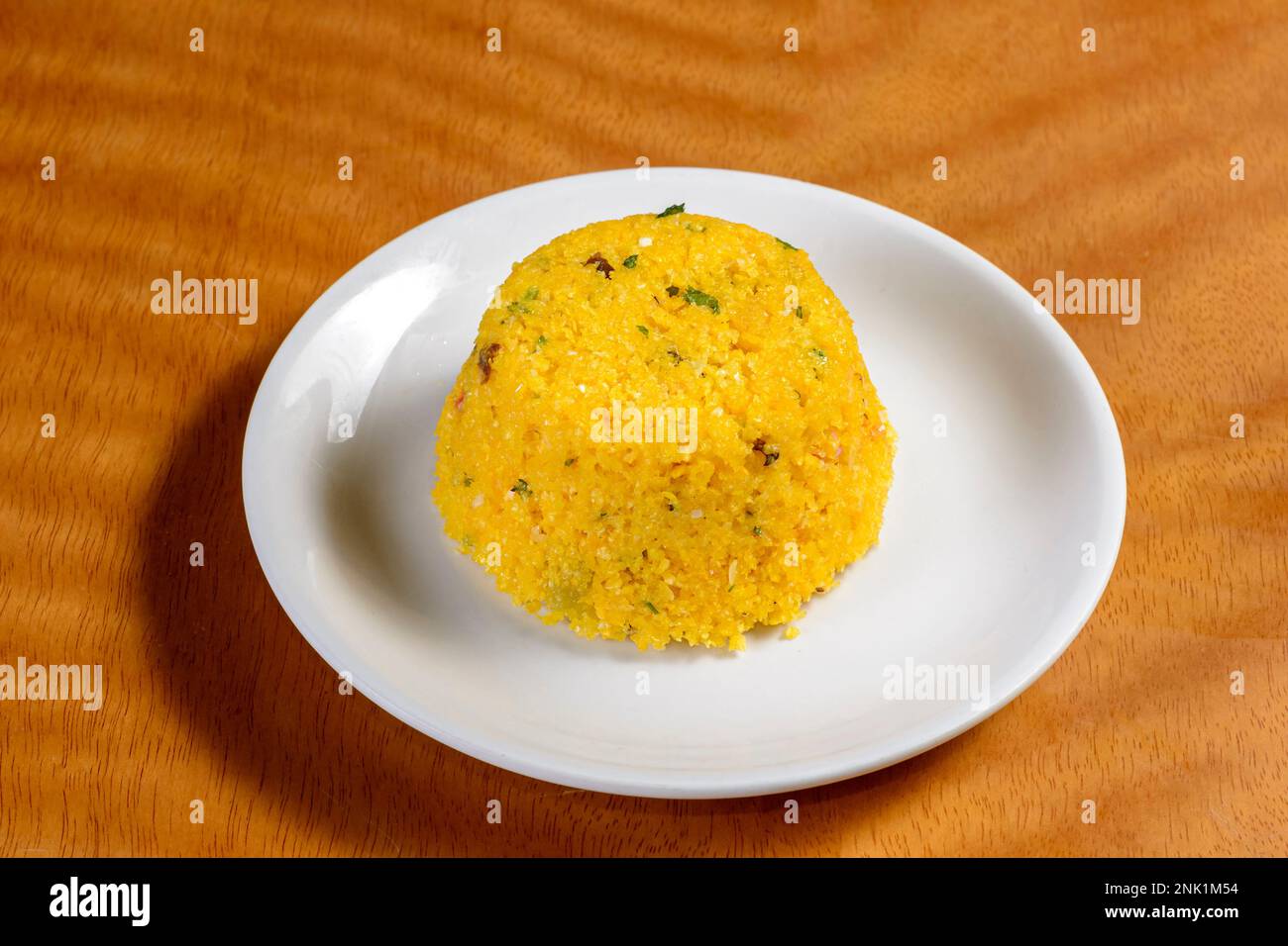 Couscous dalla regione nord-orientale del Brasile su un piatto bianco su un tavolo di legno. Foto Stock