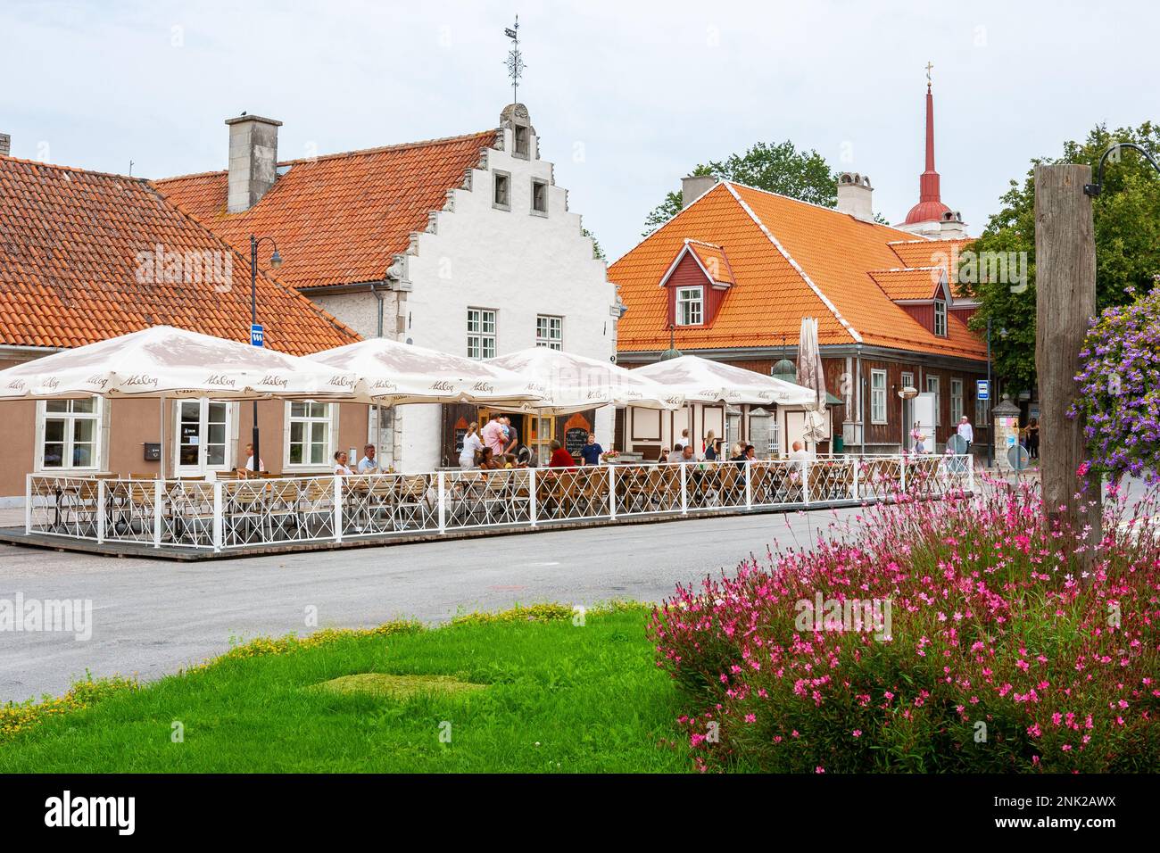 La gente è seduta sulla terrazza estiva prima di edifici storici nel centro storico di Kuressaare. Saaremaa, Estonia Foto Stock