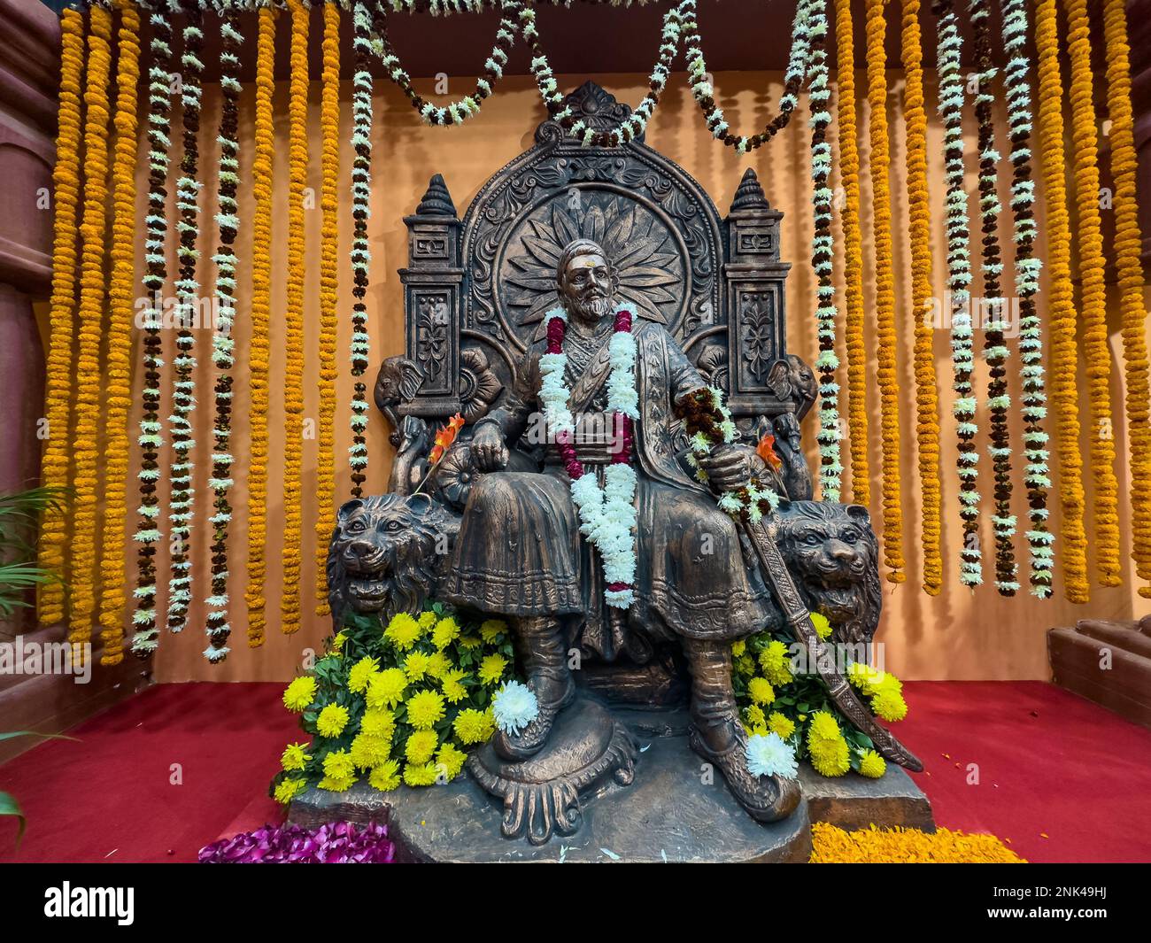 Nuova Delhi, India - novembre 2022: Grande re guerriero indù Chatrapati Shivaji Maharaj maratha. Idolo in legno Shivaji con sfondo a catena di fiori appeso. Foto Stock