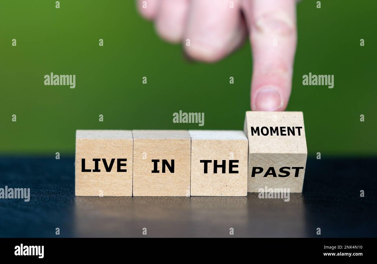 La mano gira il cubo di legno e cambia l'espressione "vivere nel passato" in "vivere nel momento". Foto Stock
