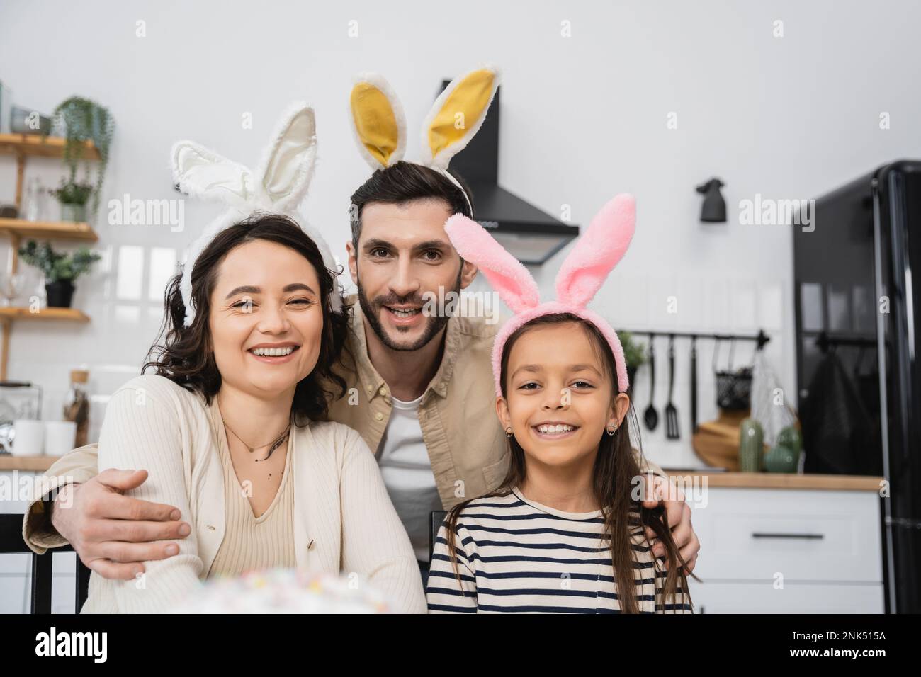 Famiglia positiva in Pasqua fascia guardando la fotocamera in cucina Foto Stock