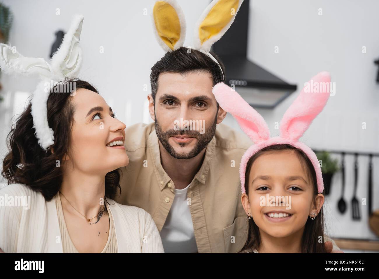 Famiglia allegra in fascia di Pasqua guardando la fotocamera a casa Foto Stock