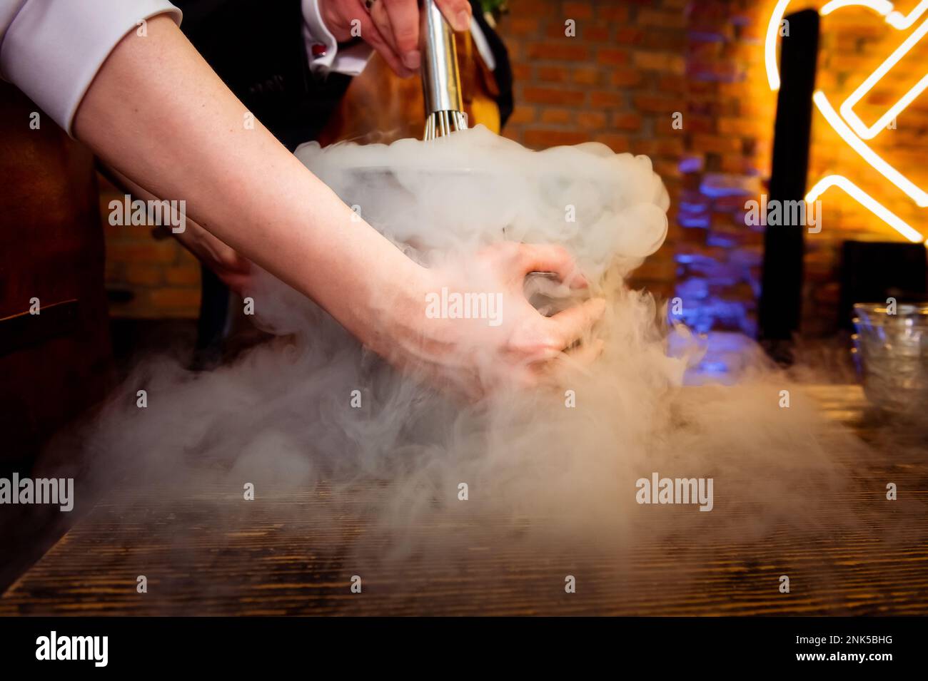 preparazione del gelato con le mani femminili dell'azoto liquido che tengono una ciotola nei fumi Foto Stock